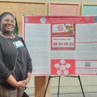 Keylaiha Brown standing in front of her poster presentation
